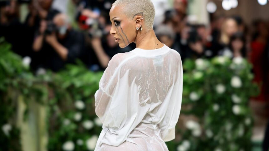 Sprei Sebelum hari Met Gala, tepatnya pada Minggu 5 Mei 2024, penyanyi Say So itu menyusuri kota New York hanya berbalut kain putih bak sprei. Dia tertangkap kamera sedang berjalan bersama desainer label Vetements, Guram Gvasalia. Bersama dengan kain sprei itu, perempuan bernama asli Amala Ratna Zandile Dlamini mengenakan pumps hitam dari Christian Louboutin. Handuk NEW YORK, NY - MAY 6: Doja Cat departs New York's luxury Mark Hotel on Monday (May 6) to head to the star-studded Met Gala in New York, United States on May 06, 2024. (Photo by Lokman Vural Elibol/Anadolu via Getty Images) Doja Cat pakai handuk/ Foto: Anadolu via Getty Images/Anadolu Busana nyeleneh berikutnya dikenakan sesaat sebelum berangkat ke Met Gala. Pada Senin (6/5), Doja Cat keluar dari Mark Hotel berbalut handuk putih lengkap dengan handuk serupa menggulung rambutnya. Kalung berlian dan platform heels turut dikenakan. Doja Cat percaya diri dalam penampilan seperti baru mandi itu lalu menuju Met Gala. Baca Juga : Kumpulan Momen Viral Met Gala 2024, Stray Kids Korban Roasting Fotografer hingga Kontroversi Kim Kardashian Kaus Basah Penampilan Doja Cat di Met Gala 2024 yang digelar di The Metropolitan Museum of Art, New York, Senin (6/5/2024) Doja Cat di Met Gala 2024/ Foto: Getty Images/Jamie McCarthy Penampilan dengan handuk berhasil mengecoh publik yang mengira itu adalah penampilan finalnya untuk ke Met Gala. Di green carpet, Doja Cat menyuguhkan gaya tak terduga, yakni wet look. Melekat pada dirinya adalah kaus putih panjang tampak basah serta riasan “menangis glitter” hasil karya makeup artist Jenna Kuchera dari Pat McGrath Labs. Kaus putih panjang yang dilumuri hair gel untuk beri tampilan basah dipadukannya dengan platform heels. Kalung berlian dilepaskan dari look itu. Kepada Entertainment Tonight Doja Cat mengungkap maksud di balik look tersebut yang dipilih untuk menyesuaikan dress code Garden of Time. “I know that people were going to do flowers but my flower of choice is the most used flower and it's cotton and so I wanted to do a white t-shirt also because a white T-shirt is timeless. It felt very poetic to chose this and I knew I wasn't going to blend in too much and I don't really like to blend in, so we went with this." (Saya tahu orang-orang akan menggunakan bunga tetapi bunga pilihan saya adalah bunga yang paling banyak digunakan dan itu adalah kapas, jadi saya ingin memakai kaus putih karena kaus putih tidak lekang oleh waktu. Rasanya sangat puitis memilih ini dan saya tahu saya tidak akan terlalu berbaur dan saya tidak terlalu suka berbaur, jadi kami memilih ini) Plastik Tidak berhenti di situ, outfit kontroversial berikutnya dikenakan Doja Cat setelah Met Gala. Doja Cat bepergian bersama Guram Gvasalia mengenakan dalaman warna kulit, lalu tubuhnya dibungkus plastik bening ukuran besar. High heels nude senada juga dikenakannya. Bagaimana tanggapanmu tentang outfit Doja Cat ini